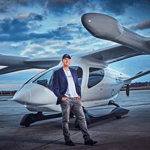 Man in a cap standing in front of an electric vertical takeoff and landing (eVTOL) aircraft