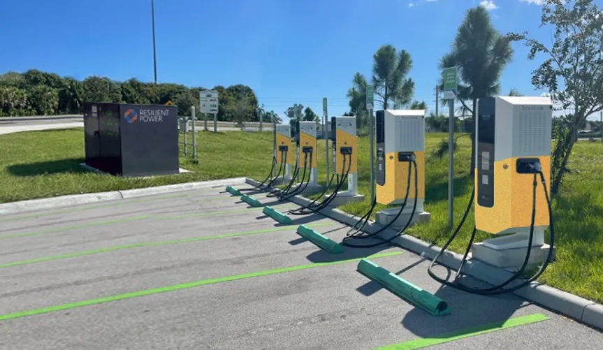 Row of electric vehicle charging stations surrounded by grass and trees